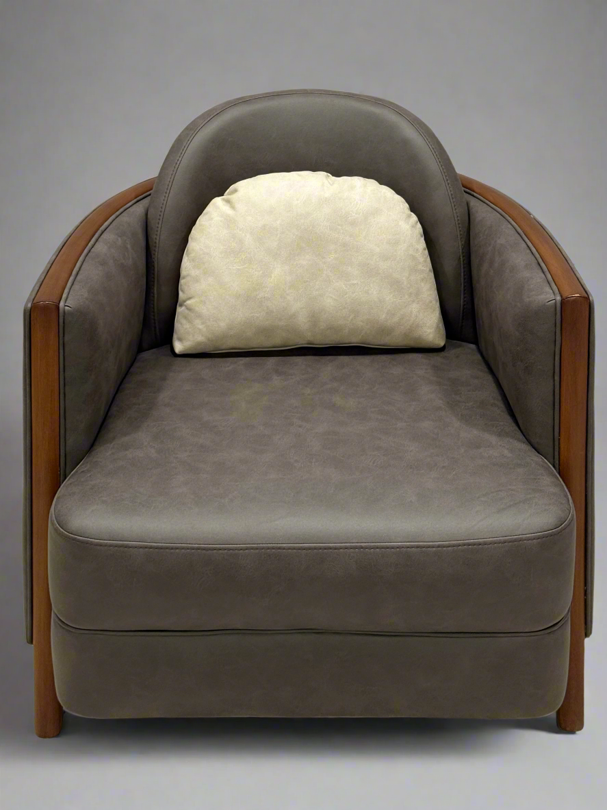 Gray armchair with a wooden frame and a white pillow on a textured floor.