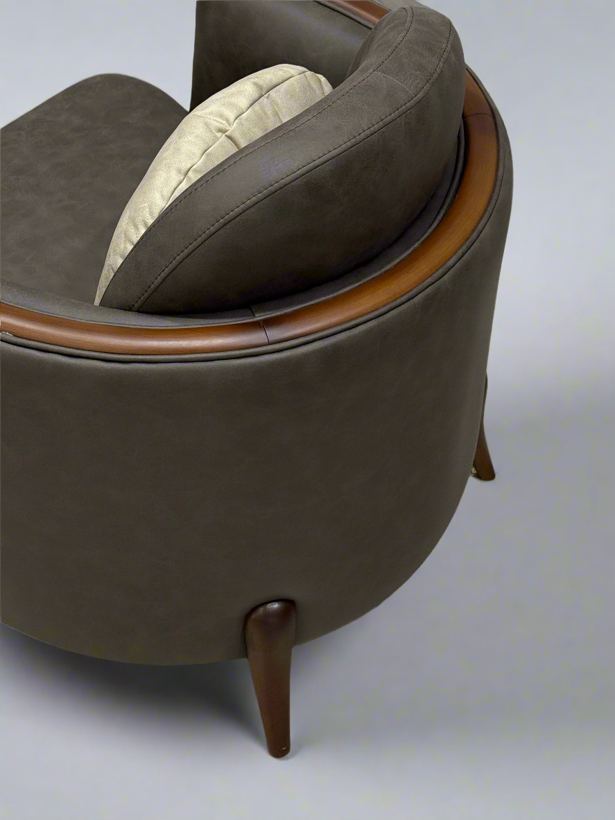 Brown leather armchair with wooden legs on a textured floor.